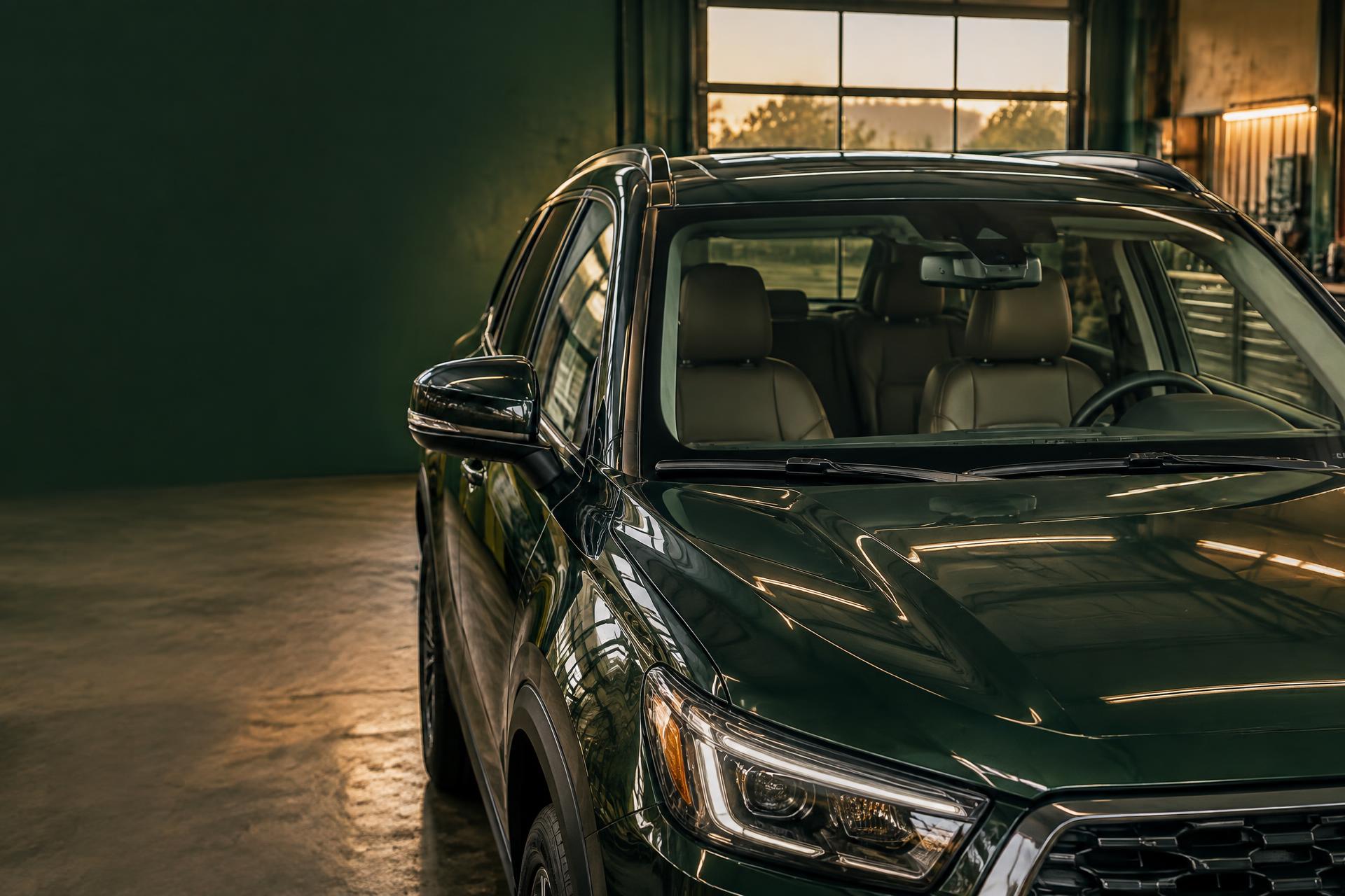 Clear windshield on a dark green SUV inside an automotive glass workshop